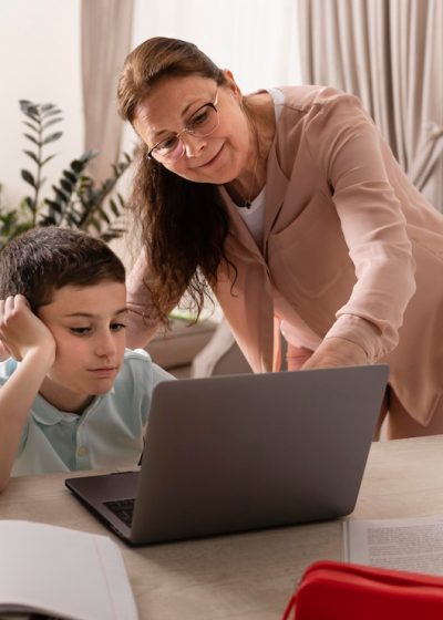 little-boy-doing-homework-with-his-grandmother-laptop_23-2148980602